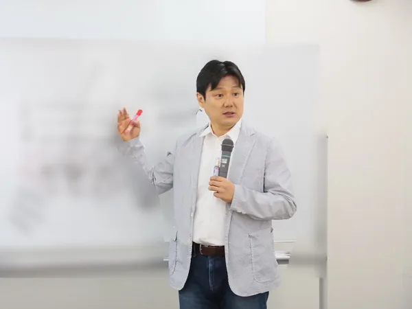 ホワイトボードの前で、肌のしくみを説明する講師